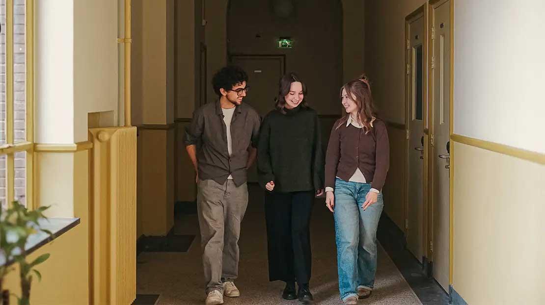 Students walking down the dorm hallway, talking.