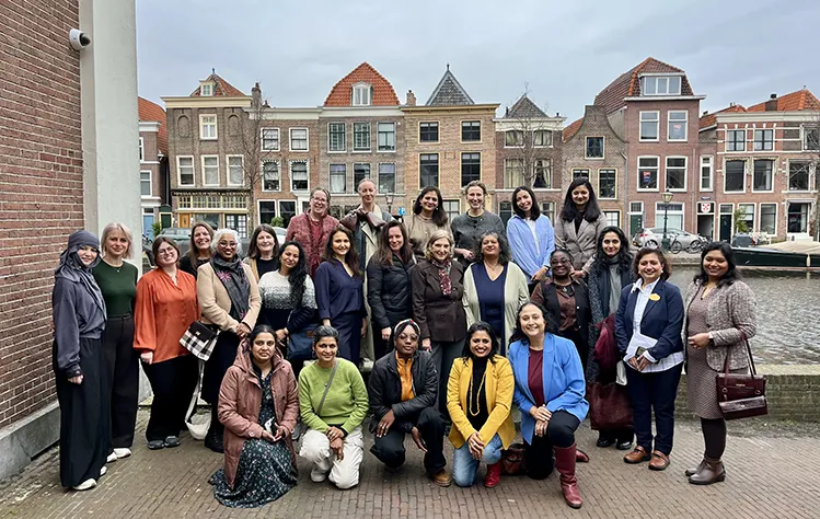 Attendees of the program launch event pose for a group photo together along the canal outside of the Webster Leiden Campus building.