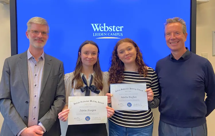 Student prize winners Jaycie Haugen and Amelia Hughes post with professor Jonathan Talbott (far left) and campus director Jean Paul van Marissing (far right).